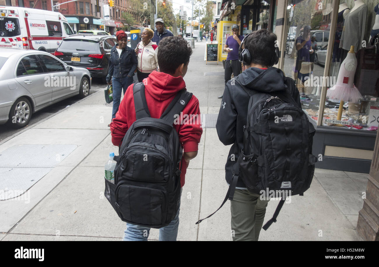 Due amici con zaini pieni di libri a piedi giù 7th Avenue a Park Slope, Brooklyn sul loro modo di scuola di mattina. Foto Stock