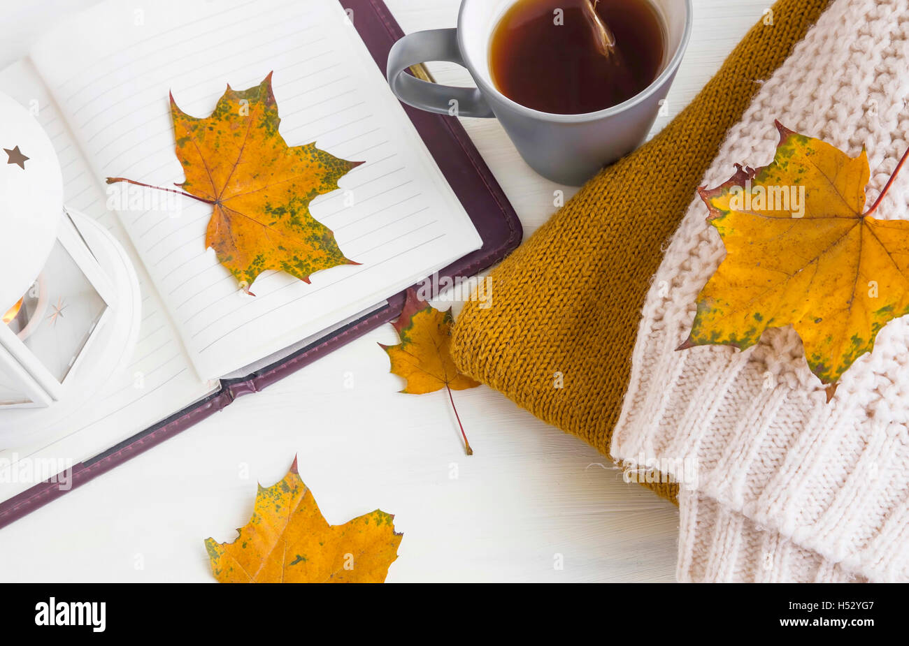 In autunno la vita ancora con la lanterna, notebook, autunno foglie essiccate, tazza da tè e accoglienti i maglioni di lana Foto Stock