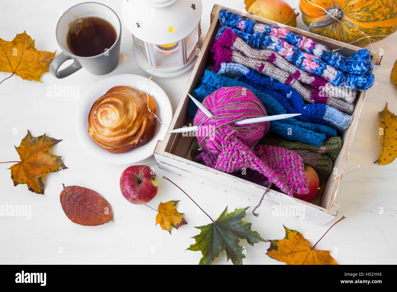Lana per maglieria e gli aghi con candela lanterna, essiccato Foglie di autunno,mele,tazza da tè Foto Stock