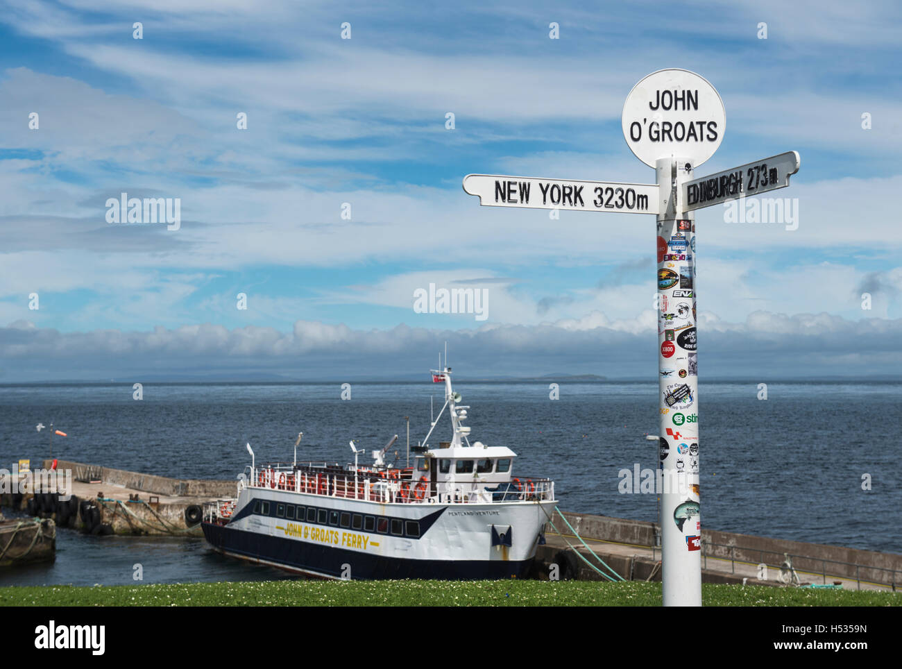 Il famoso multi-direzionale del cartello a John O'Semole di Caithness in Scozia, con John O'semole ferry in background Foto Stock