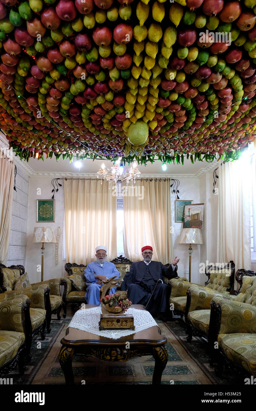 Il sommo sacerdote dei samaritani, Abdallah Wasef ( L) e suo fratello seduti intorno a un fruttato Sukkah realizzato da quattro specie nella loro casa in kiryat luza villaggio vicino alla città di Nablus in Cisgiordania Israele il 18 ottobre 2016. I samaritani che fanno risalire le proprie radici del regno settentrionale di Israele in che cosa ora è la Cisgiordania settentrionale osservare le pratiche religiose simili a quelli del giudaismo. Durante Sukkot holiday samaritani costruire loro sukkot dentro la loro casa a differenza di ebrei che costruiscono il loro all'esterno. Foto Stock