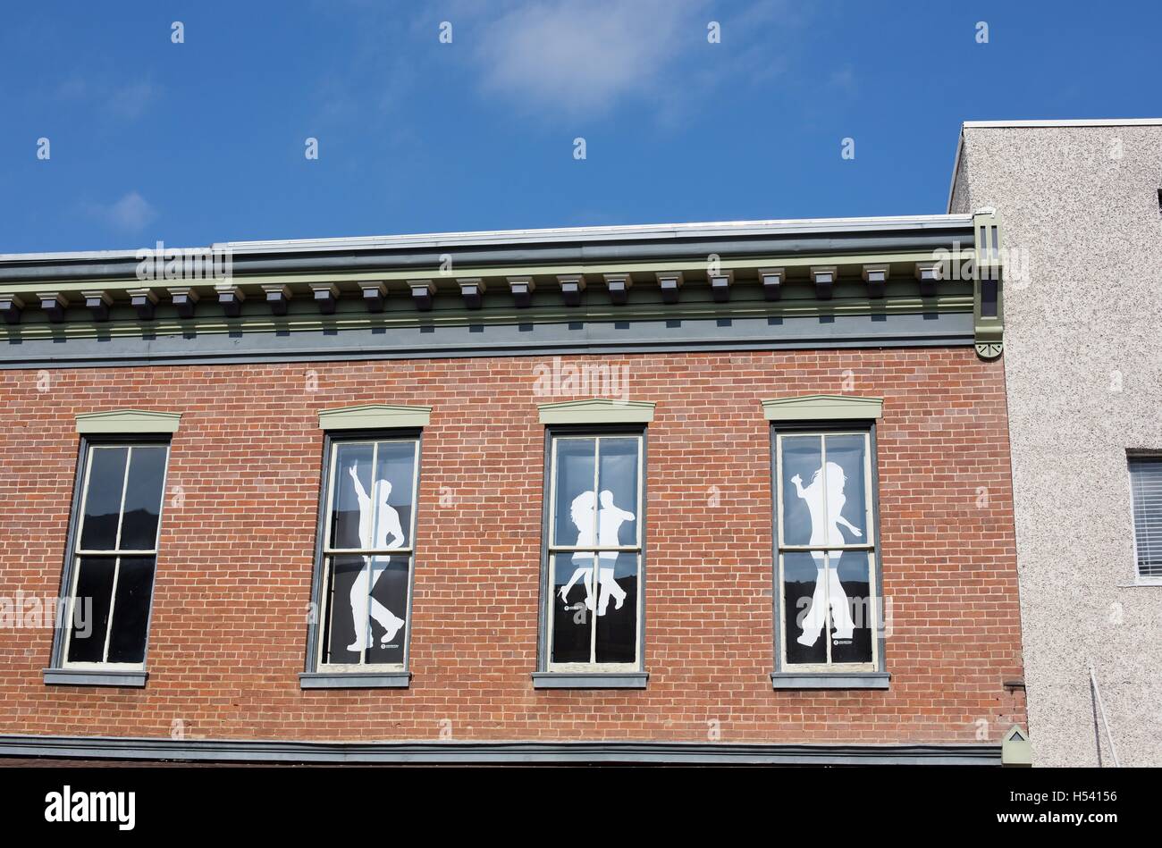 Ritaglio sagome di persone che ballano nelle finestre di un edificio. Foto Stock