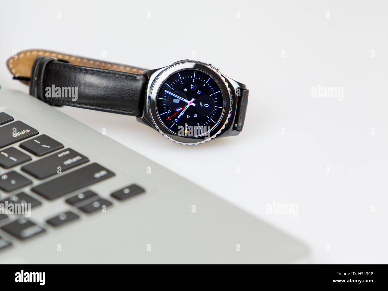 Lapto pcon smart watch giacente sul lato sinistro del notebook. orologio sul display e la batteria è completamente carica. 4 o clock sul wa Foto Stock