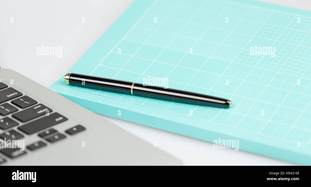 Penna chiusa su un blu chiuso notebook e laptop in un background. studio shot su sfondo bianco Foto Stock