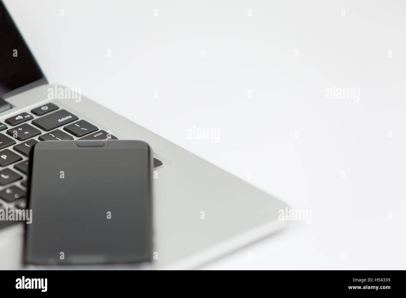 Smartphone giacente sulla parte superiore del portatile. sia spento. studio shot su sfondo bianco Foto Stock