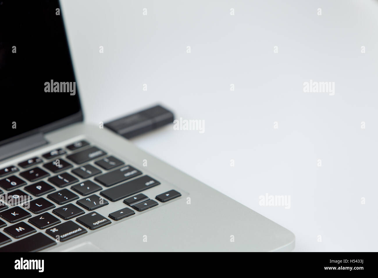 Un black stick USB inserito sul lato destro del portatile. closeup shot con focus sulla tastiera Foto Stock