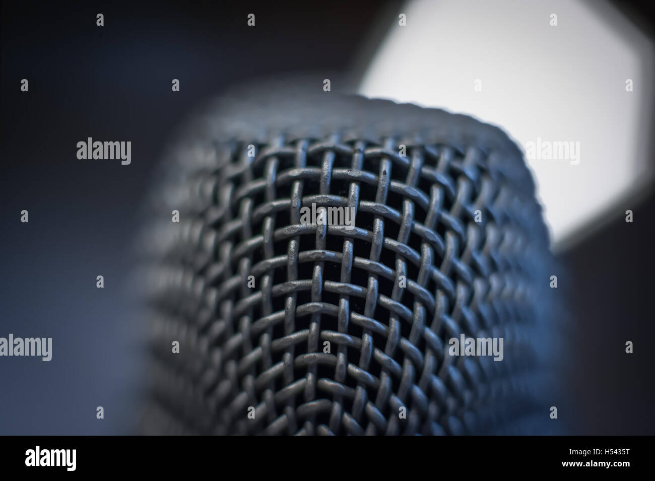 Nero moderno studio microfono testa macro close up con fuori fuoco freddo luce blu in alto a destra sullo sfondo Foto Stock
