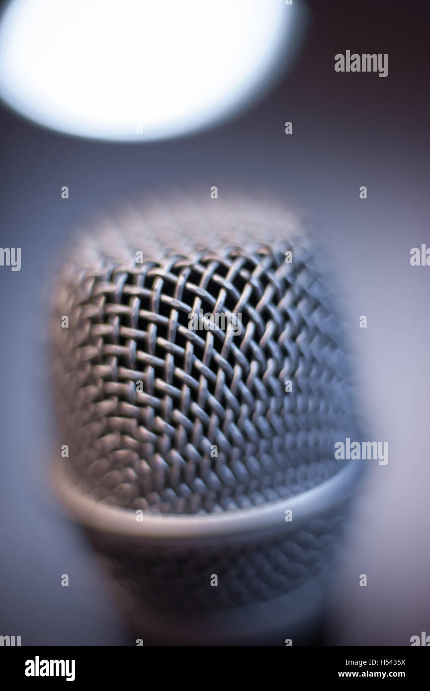 Nero moderno studio microfono testa macro close up con fuori fuoco freddo luce blu sulla parte superiore in background Foto Stock