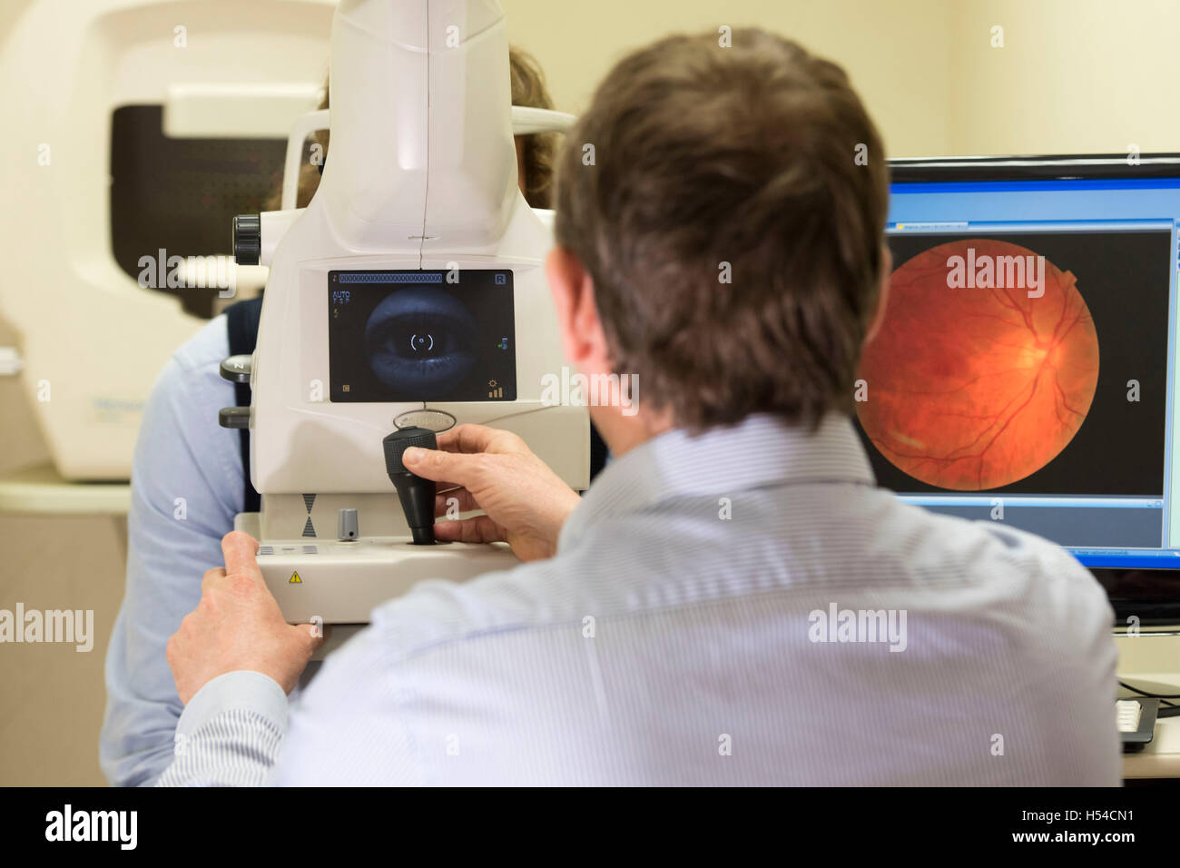 Un ottico effettuando un occhio test utilizzando una tomografia di coerenza ottica (PTOM) macchina. Foto Stock