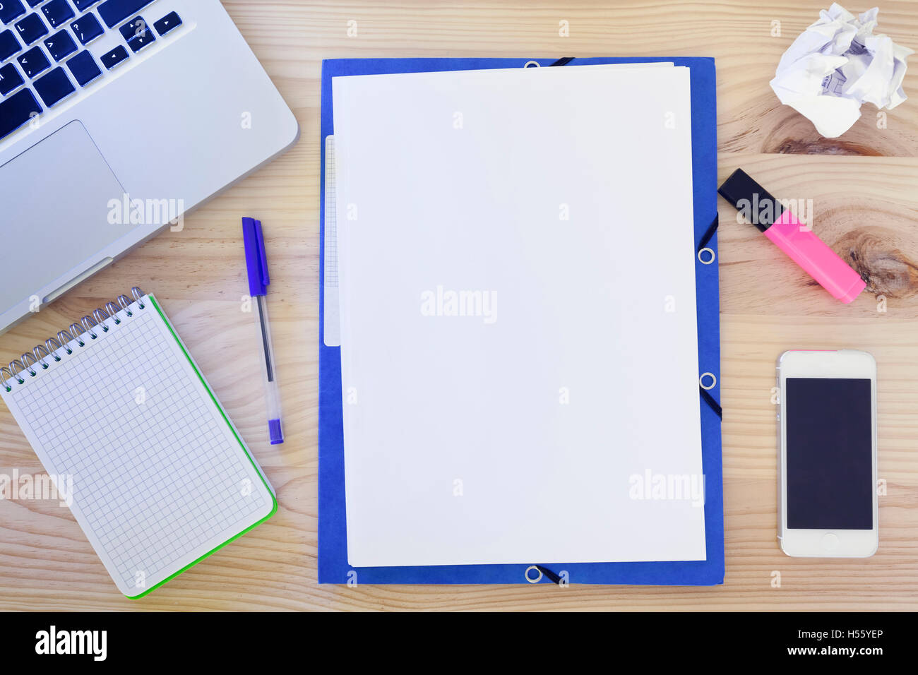 Top-vista della scrivania di legno con carta bianca al centro, un computer portatile e di forniture per ufficio, il concetto di creatività Foto Stock