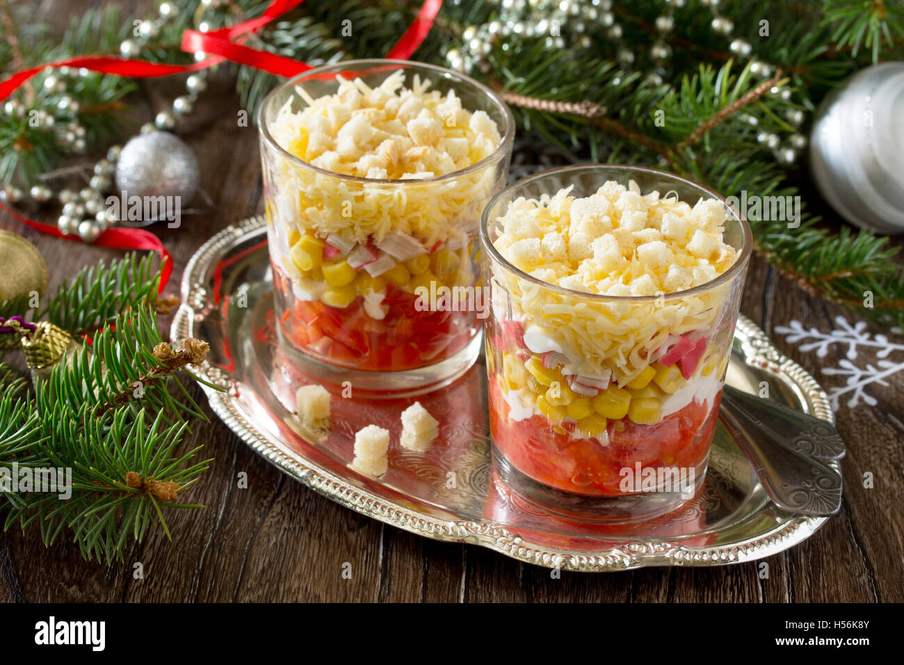 Natale con insalata di pomodori, mais e crackers su un tavolo di legno. Foto Stock