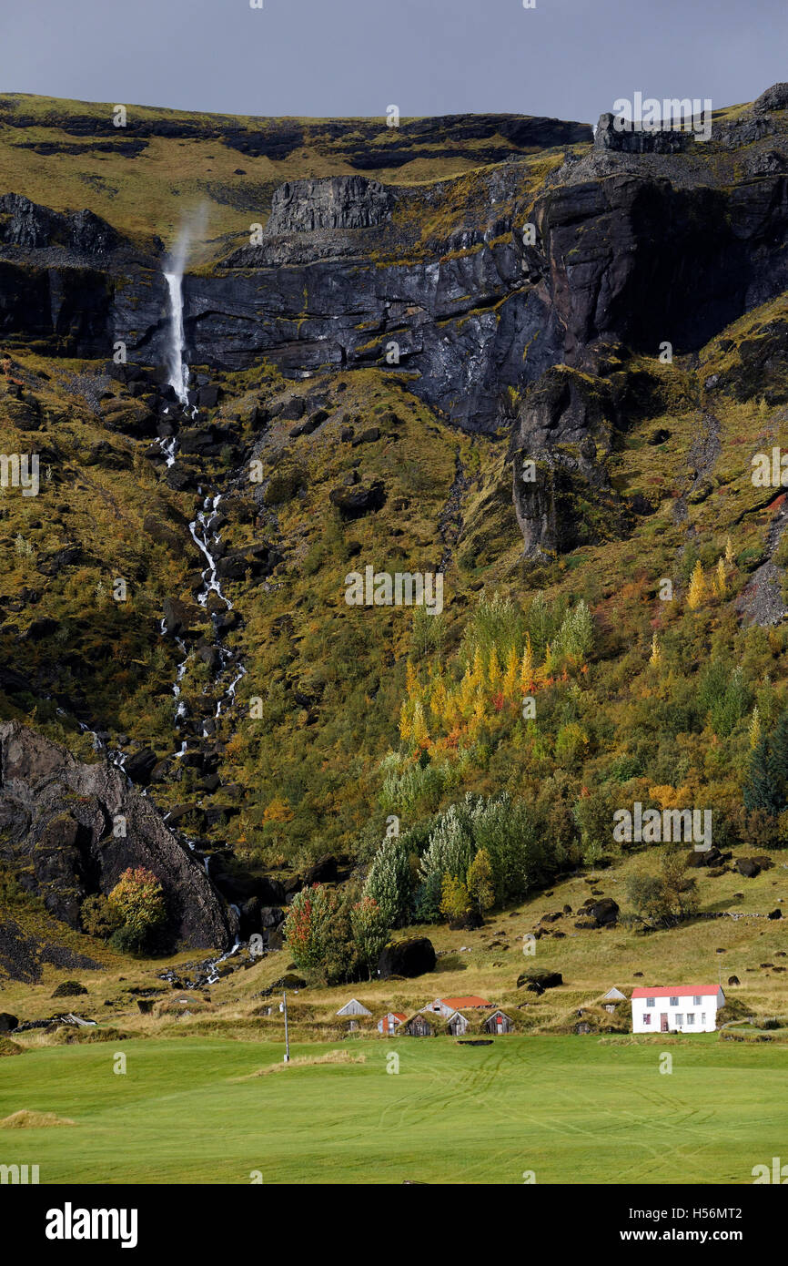 Paese rurale home sotto la cascata di montagna, Est Islanda, Atlantico del Nord, Europa Foto Stock