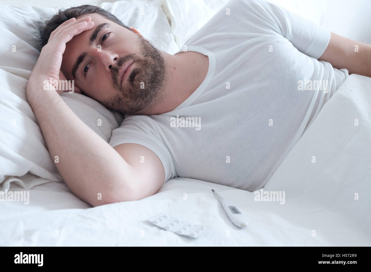 Triste uomo disteso nel letto e sensazione di cattivo Foto Stock