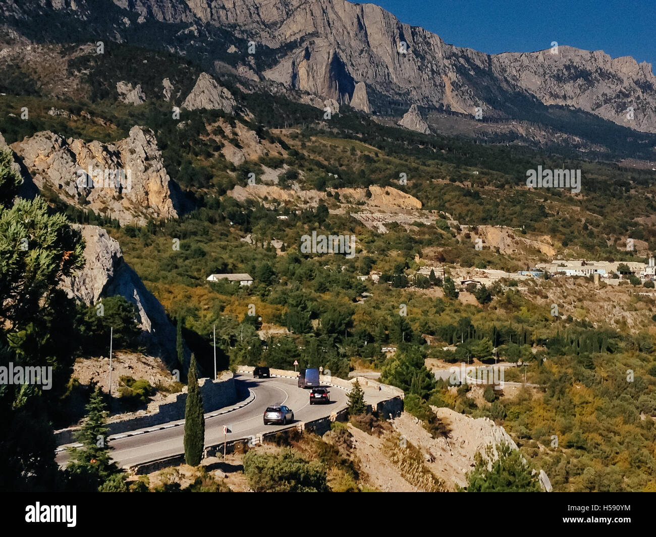 Strada di Montagna in Crimea. Cars driving lungo la serpentina strada di montagna, intorno all'autunno foresta, foglie di giallo Foto Stock