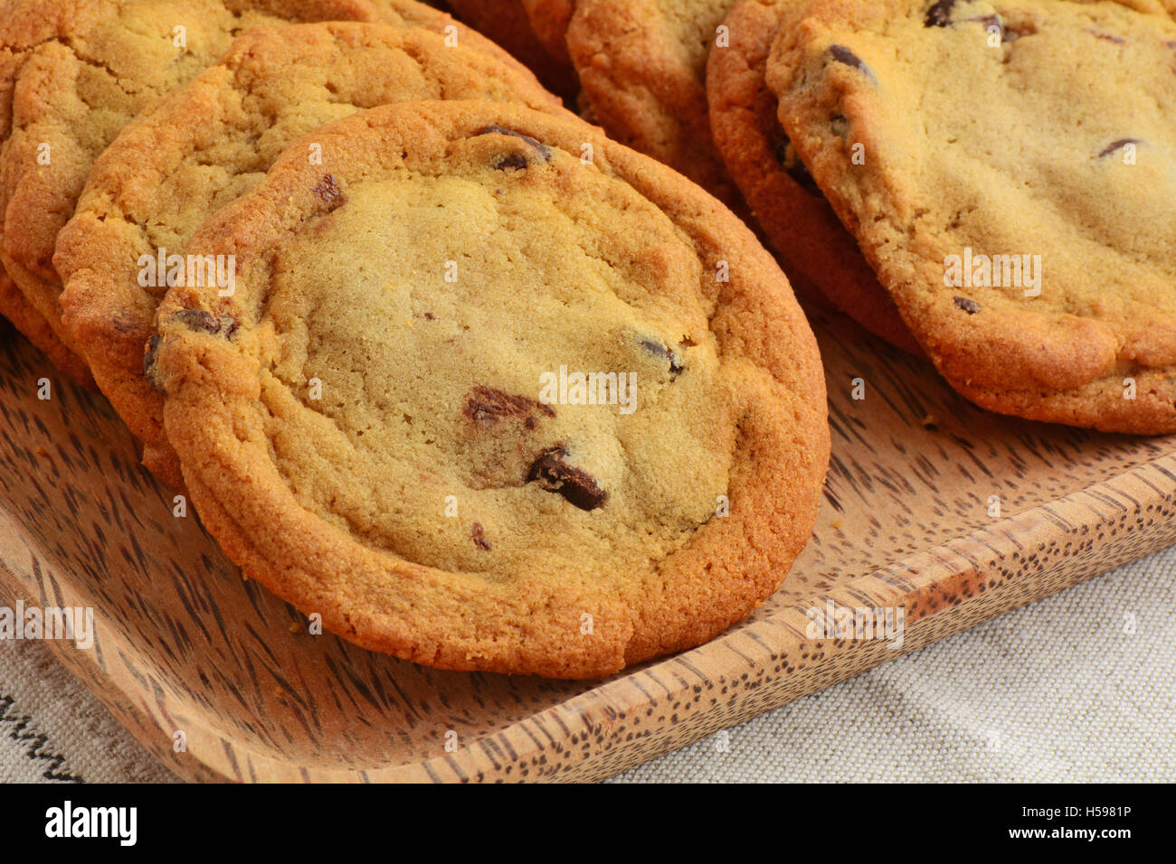 Freschi di forno biscotti con scaglie di cioccolato sul vassoio in legno in formato orizzontale. Macro con shallow DOF. Focus sulla parte anteriore cookie. Foto Stock