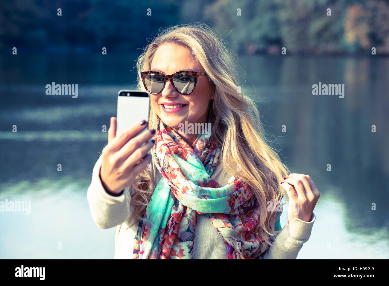 Giovane e bella bionda rendendo selfie nel parco Foto Stock