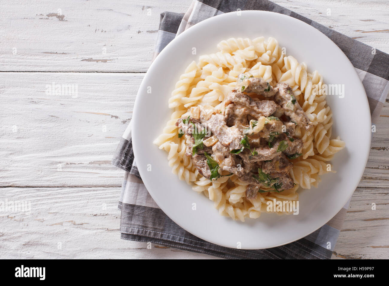 Deliziosa carne di manzo stroganoff con pasta fusilli su una piastra sul tavolo. Vista orizzontale dal di sopra Foto Stock