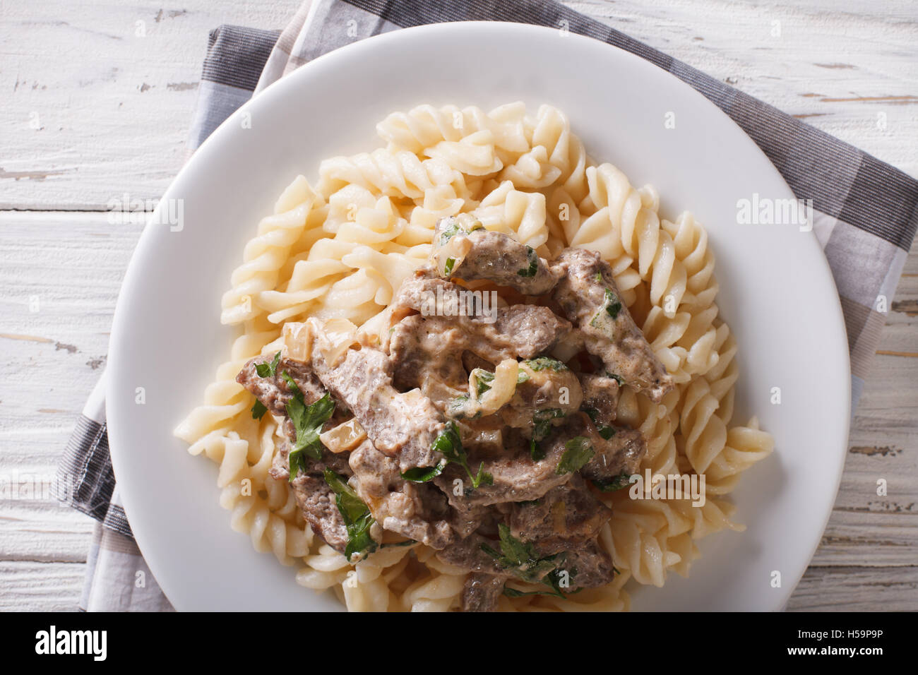 Carni bovine stroganoff e pasta fusilli close-up su una piastra sul tavolo. vista orizzontale dal di sopra Foto Stock