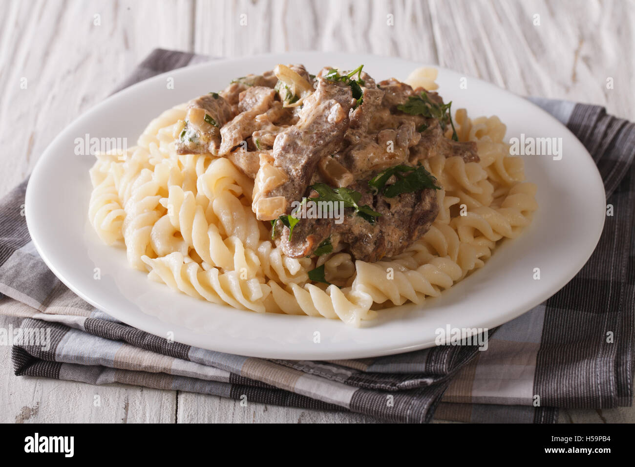 Carni bovine russo stroganoff con pasta fusilli closeup su una piastra sul tavolo orizzontale. Foto Stock