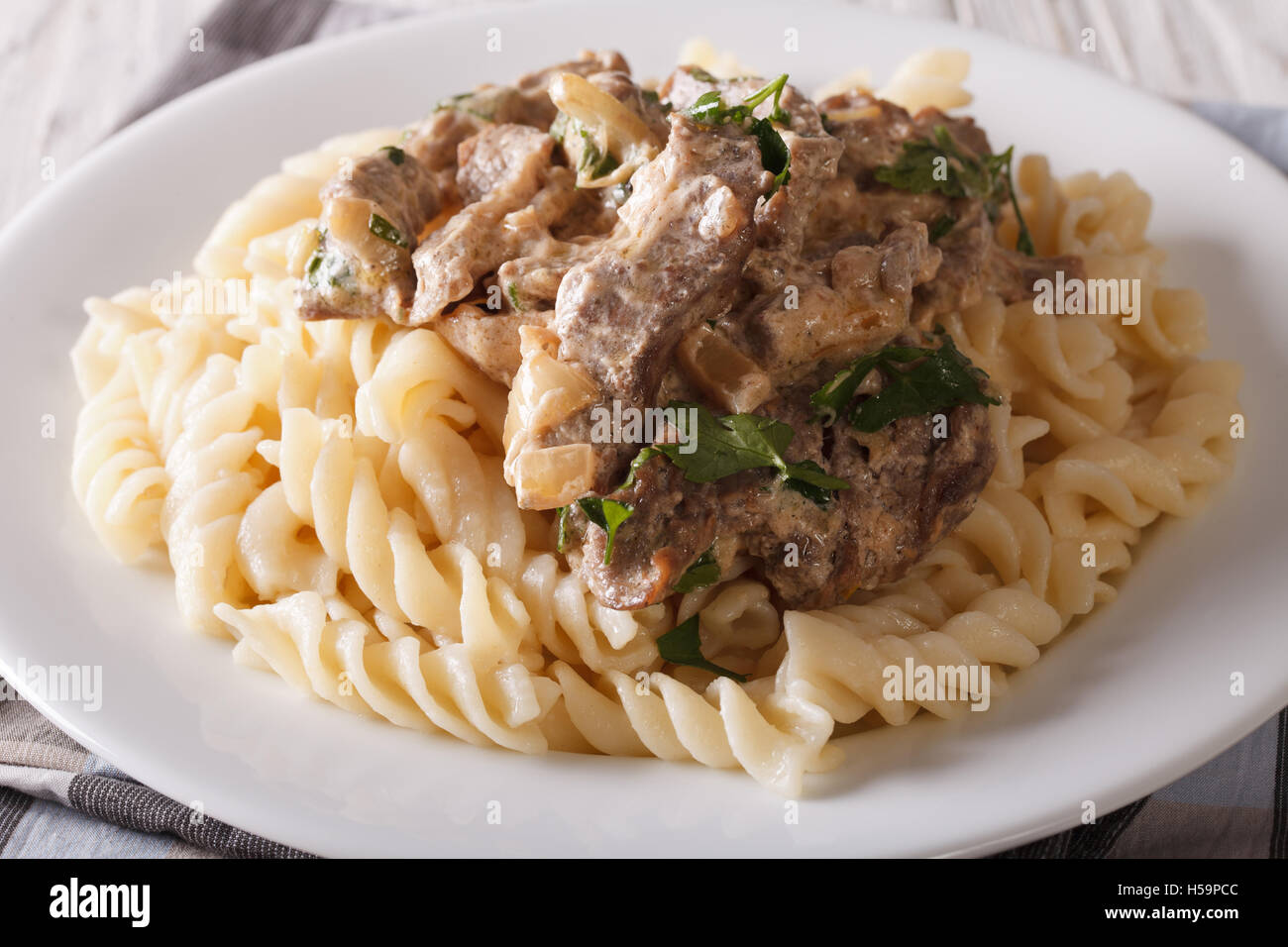 Carni bovine stroganoff con pasta fusilli closeup su una piastra sul tavolo. Posizione orizzontale Foto Stock