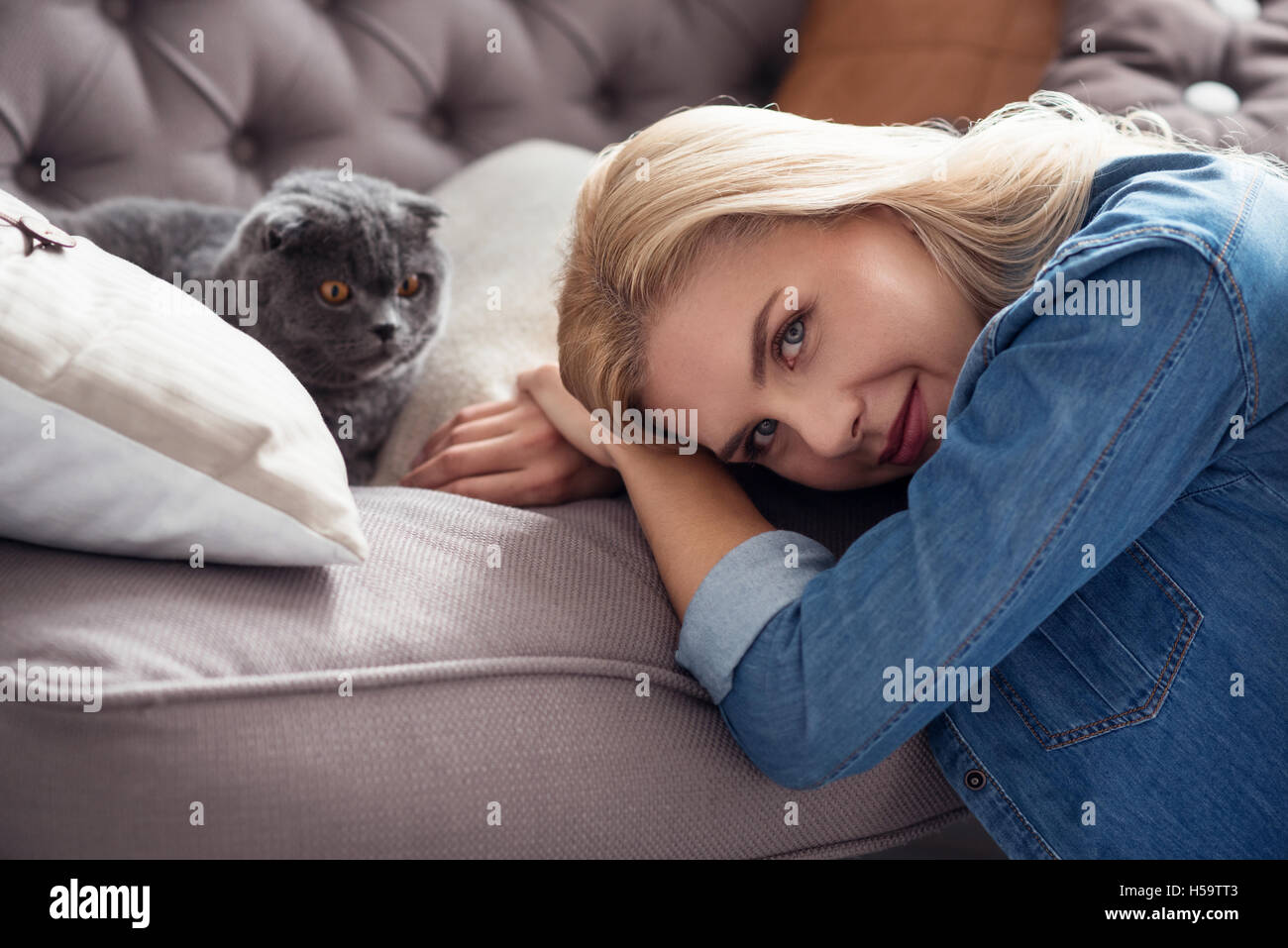 Dolce signora bionda con il suo gatto sul lettino Foto Stock