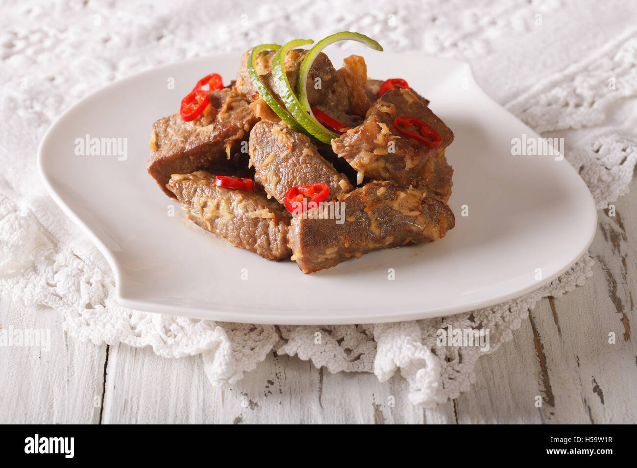 Rendang carni bovine con spezie close-up su una piastra sul tavolo orizzontale. Foto Stock