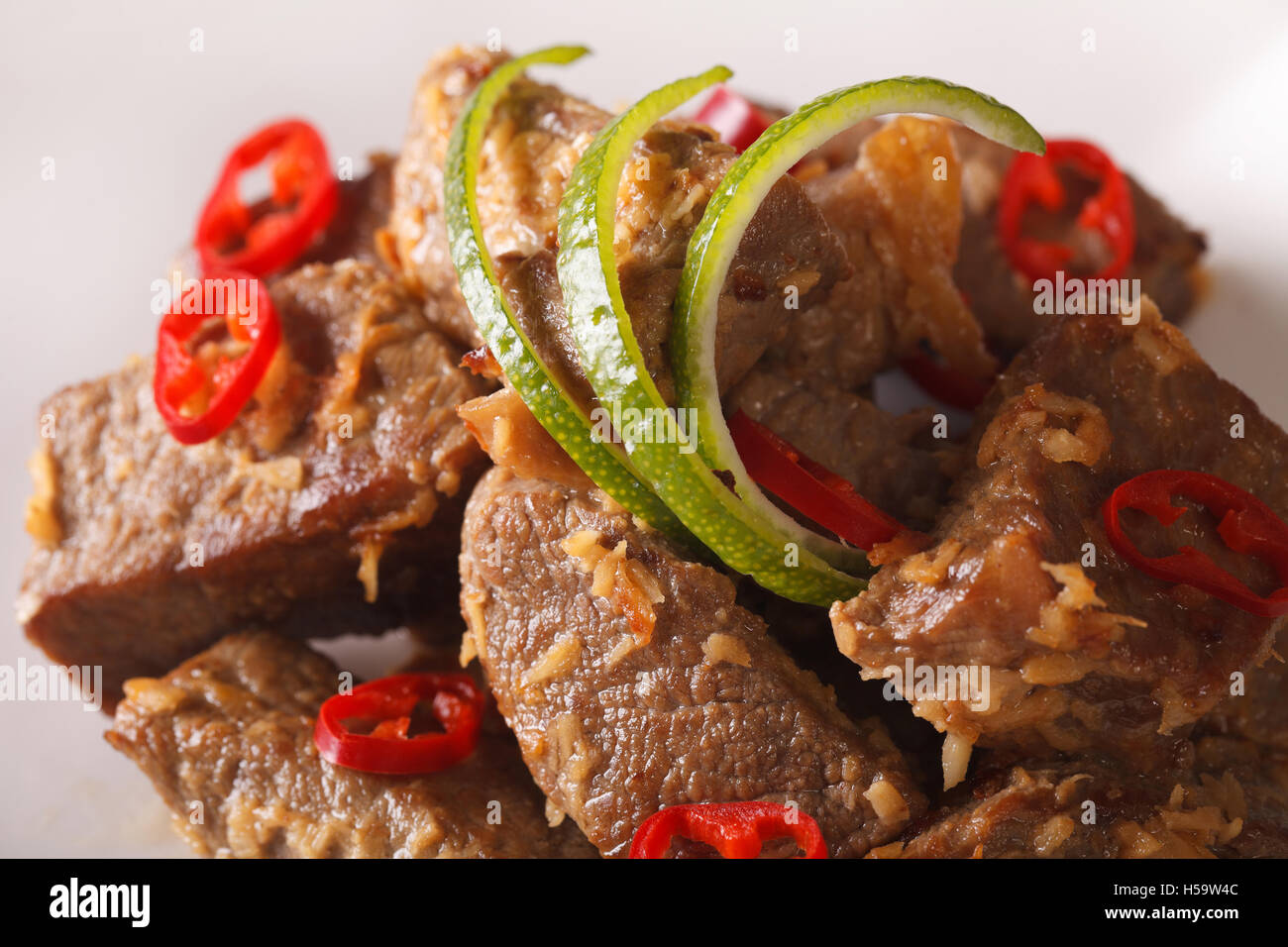 Carni bovine rendang con noce di cocco e le spezie macro su una piastra. Posizione orizzontale Foto Stock