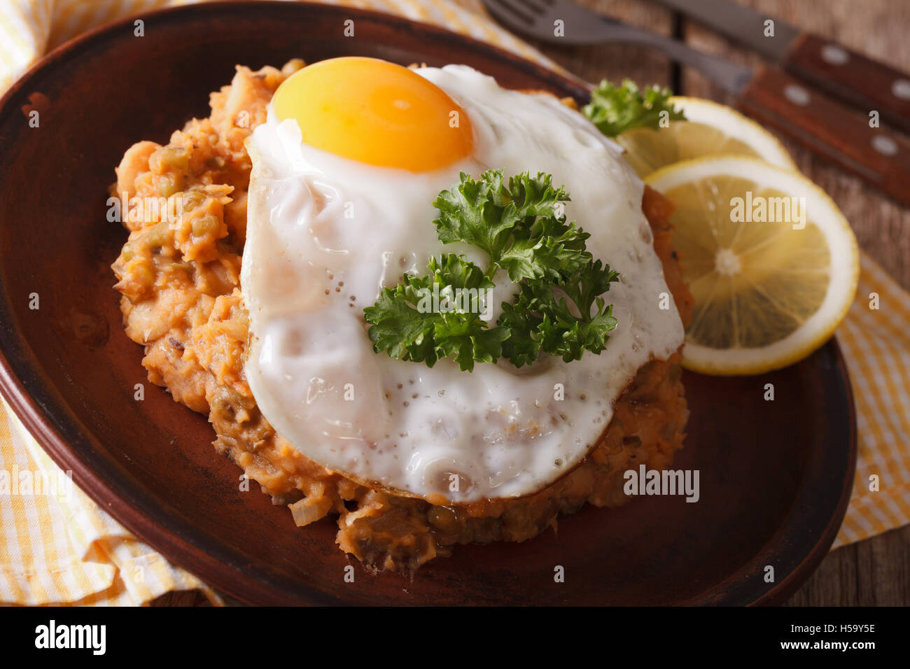 Colazione egiziano: fagioli con un uovo fritto su una piastra di close-up orizzontale. Foto Stock