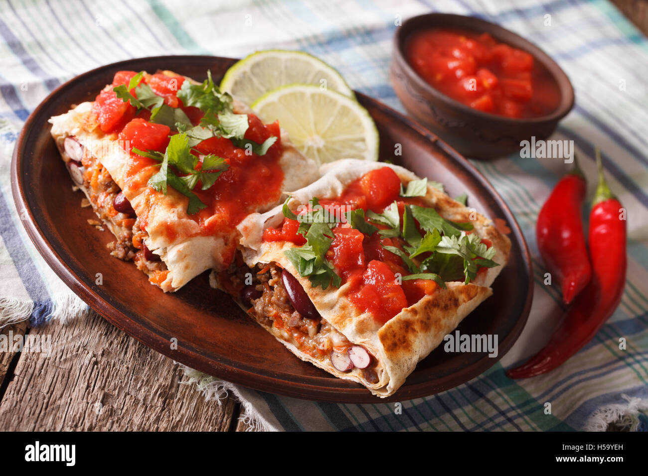 Chimichanga con carne macinata, verdure e formaggio su una piastra di close-up orizzontale Foto Stock