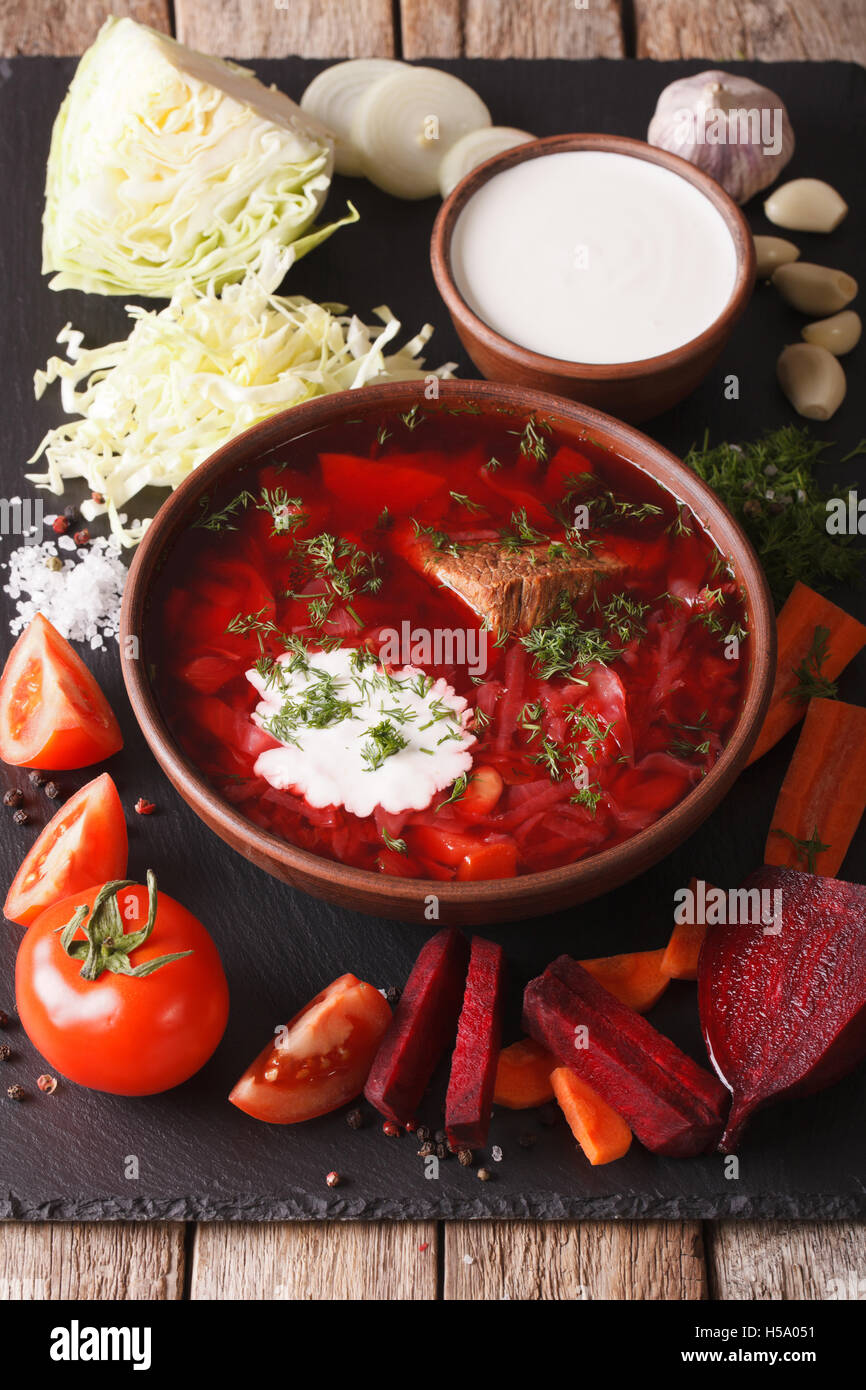 Cibo ucraino: zuppa rossa borsch con ingredienti sulla scheda di ardesia closeup verticale. Foto Stock