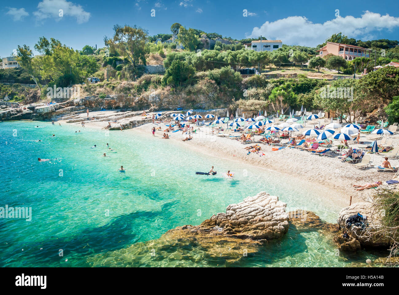 Kassiopi Beach, l'isola di Corfù, Grecia. Lettini e ombrelloni (ombrellone) sulla spiaggia. I turisti rilassante sulla spiaggia. Foto Stock