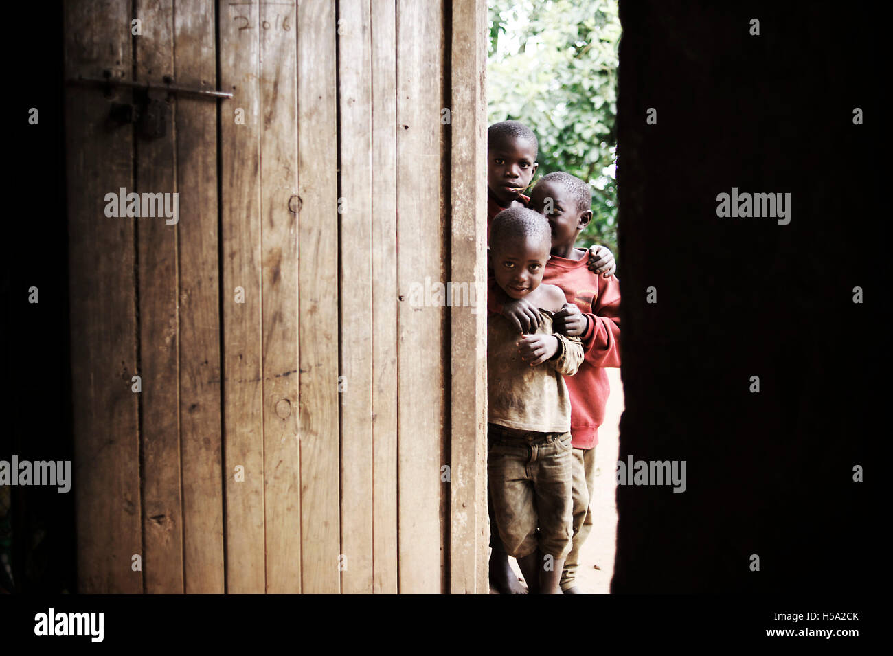 Un gruppo di bambini africani guardano attraverso una porta all'occidentale nella loro casa Foto Stock