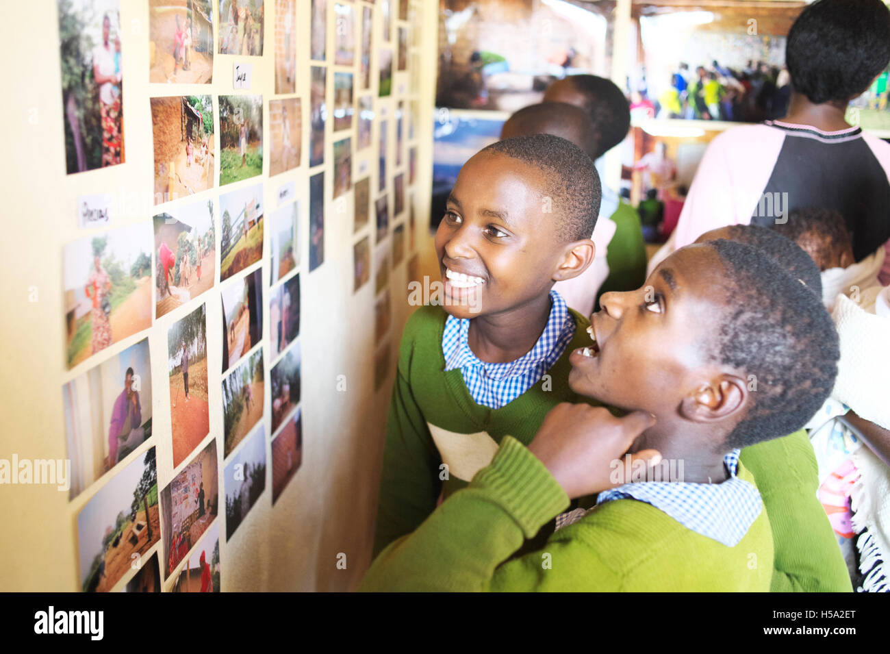 Due East African bambini ugandesi guardare una parete di fotografie nella loro rurale scuola ugandese con la felicità sui loro volti Foto Stock