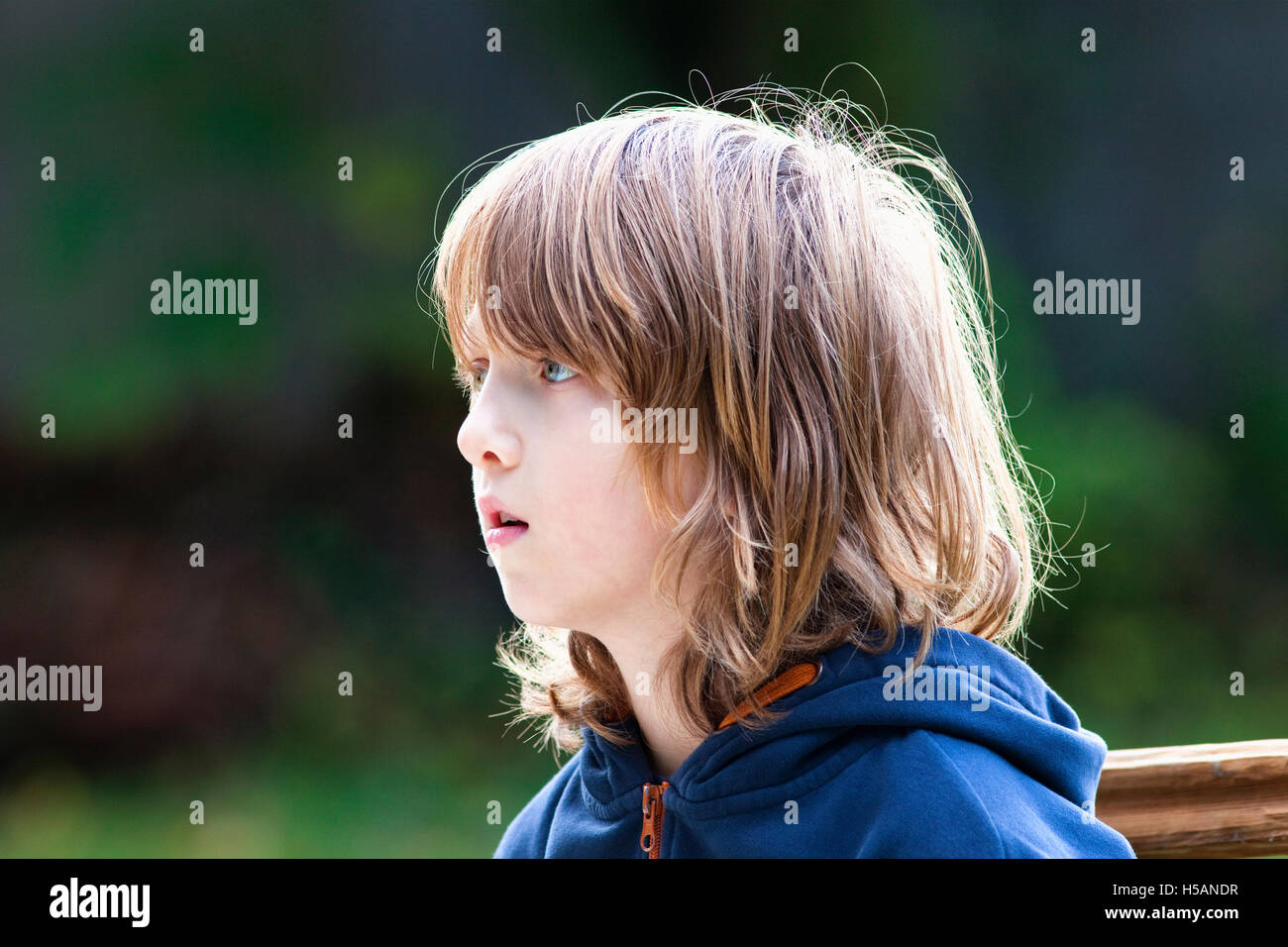 Ritratto di un ragazzo con lunghi capelli biondi all'aperto Foto Stock