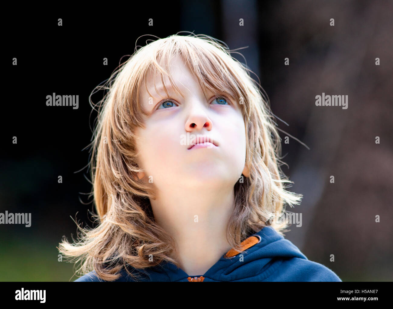 Ritratto di un ragazzo con lunghi capelli biondi all'aperto Foto Stock