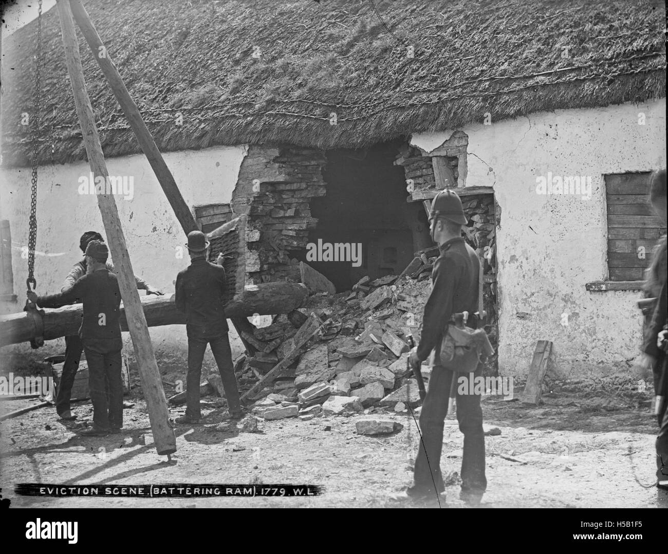 Una fotografia che raffigura una scena di sfratto in cui un ariete viene utilizzato per abbattere una porta. Questa immagine drammatica cattura un momento nella storia in cui gli sfratti sono stati effettuati con forza durante periodi di disordini sociali o difficoltà economiche. Foto Stock
