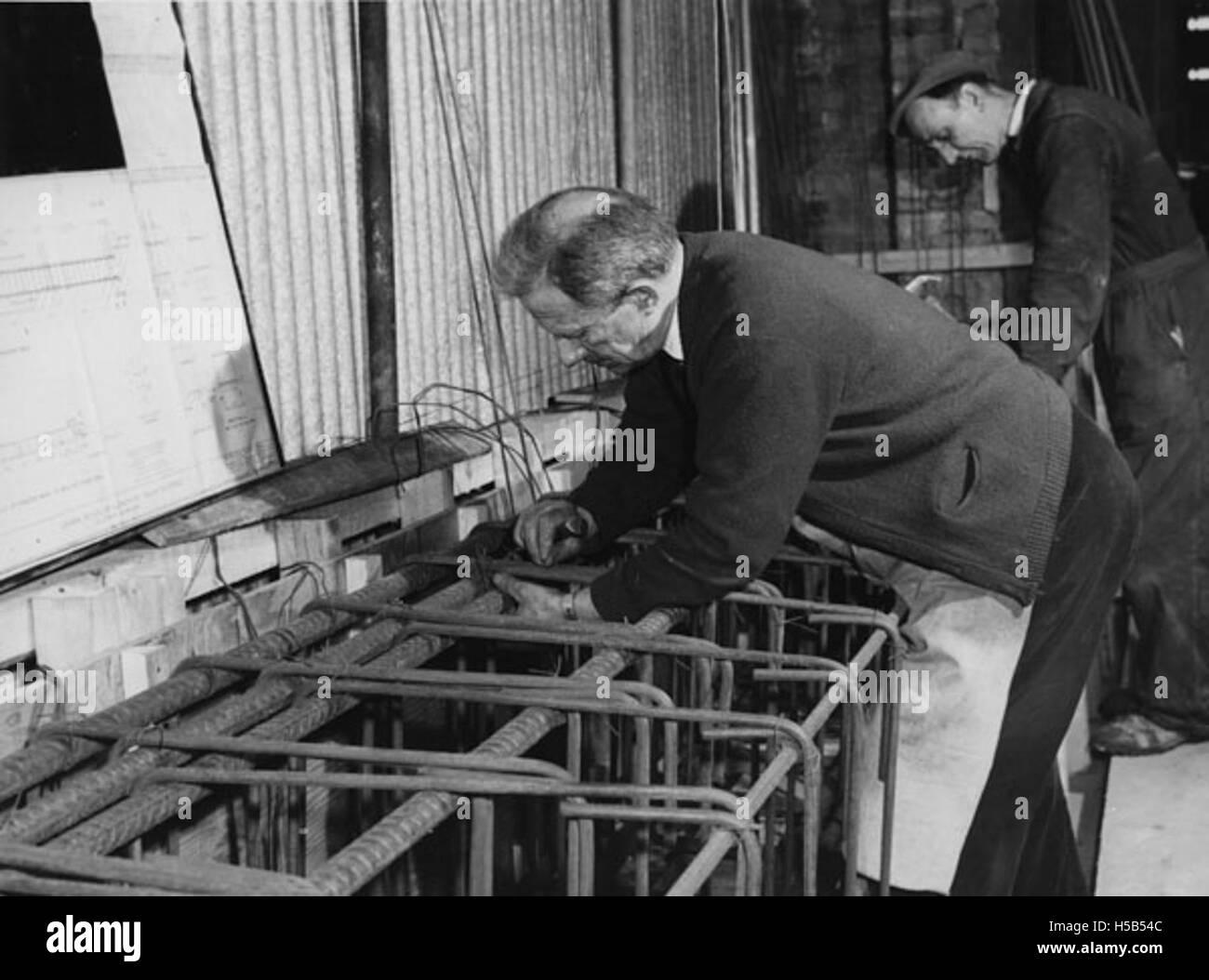 Questa immagine cattura gli operai in un cantiere nel 1964, mostrando probabilmente il loro coinvolgimento nello sviluppo di edifici o infrastrutture. Riflette le tendenze industriali e del lavoro degli anni '1960 Foto Stock