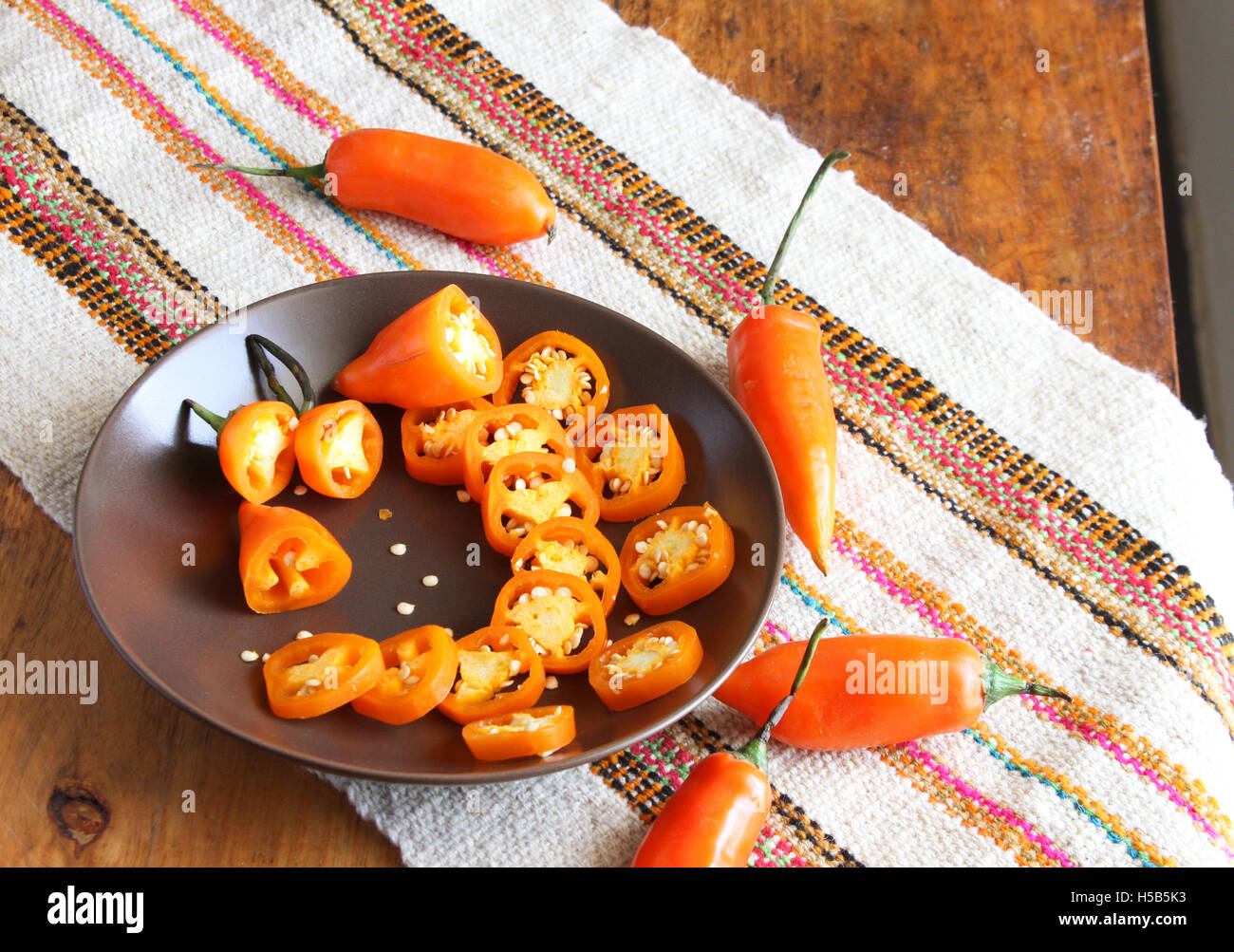 Piastra di colore arancione peperoncino anelli con semi e tutto il peperoncino sul tavolo con luogo pittoresco mat Foto Stock