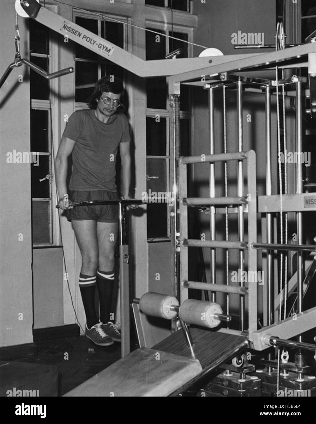 Uno studente degli anni '1970 viene visto con nuove attrezzature da palestra, che riflettono il crescente interesse dell'epoca per l'educazione fisica e il fitness. La fotografia cattura le moderne attrezzature da palestra del tempo, che hanno segnato un cambiamento nei programmi di fitness fisico basati sulla scuola durante gli anni '1970, allineandosi con le tendenze più ampie del fitness del decennio. Foto Stock