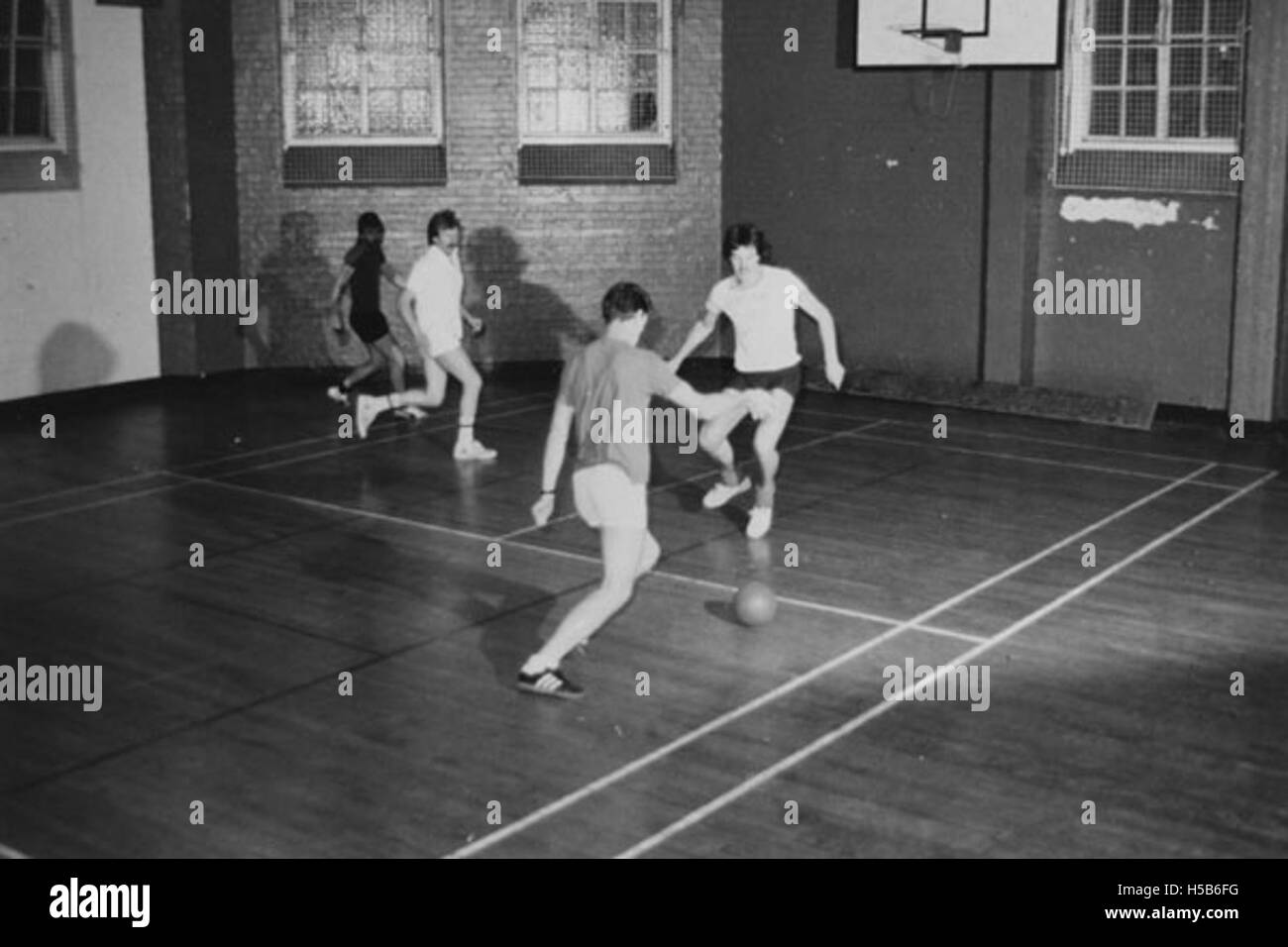 Questa foto di circa 1981 mostra un gruppo di studenti che giocano a calcio in una palestra. Mette in evidenza l'attività fisica e la cultura sportiva giovanile durante i primi anni '1980 in ambienti educativi. Foto Stock Questa foto di circa 1981 mostra un gruppo di studenti che giocano a calcio in una palestra. Mette in evidenza l'attività fisica e la cultura sportiva giovanile durante i primi anni '1980 in ambienti educativi. Foto Stock