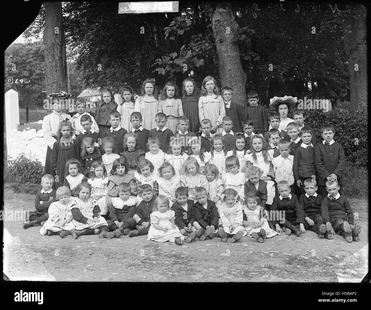 Un gruppo sconosciuto di scolari viene catturato in questo ritratto. La fotografia rappresenta probabilmente una classe o un istituto scolastico di un tempo precedente, che mostra l'abbigliamento e l'ambiente scolastico di quel periodo. Foto Stock