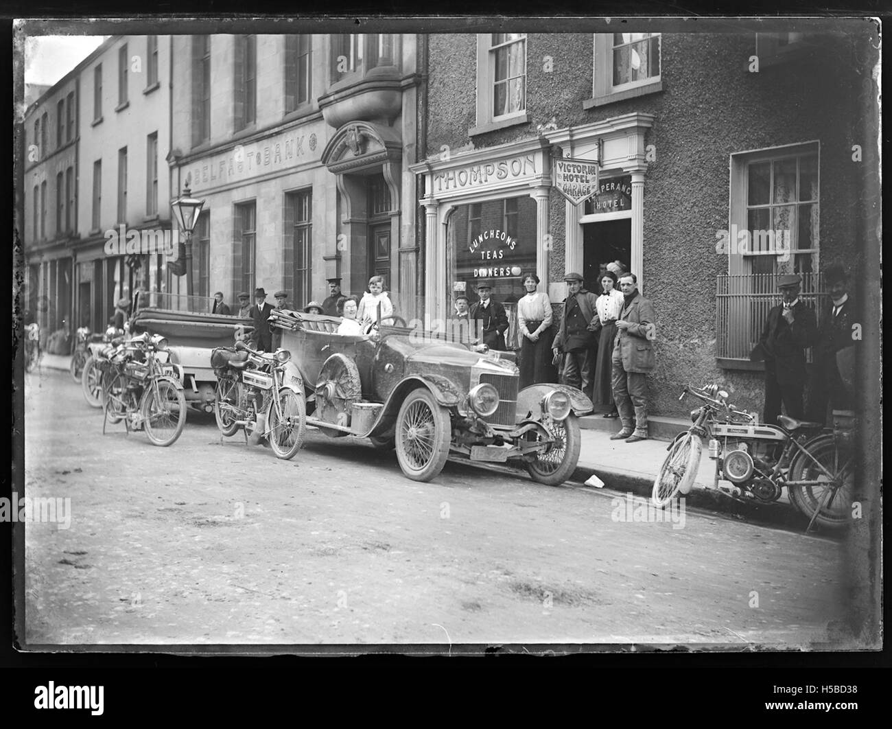 Questa immagine mostra auto e motociclette parcheggiate di fronte al Victoria Hotel, probabilmente una posizione trafficata o iconica. Mette in risalto sia i veicoli moderni che un edificio storico, enfatizzando il contrasto tra trasporto e architettura. Foto Stock