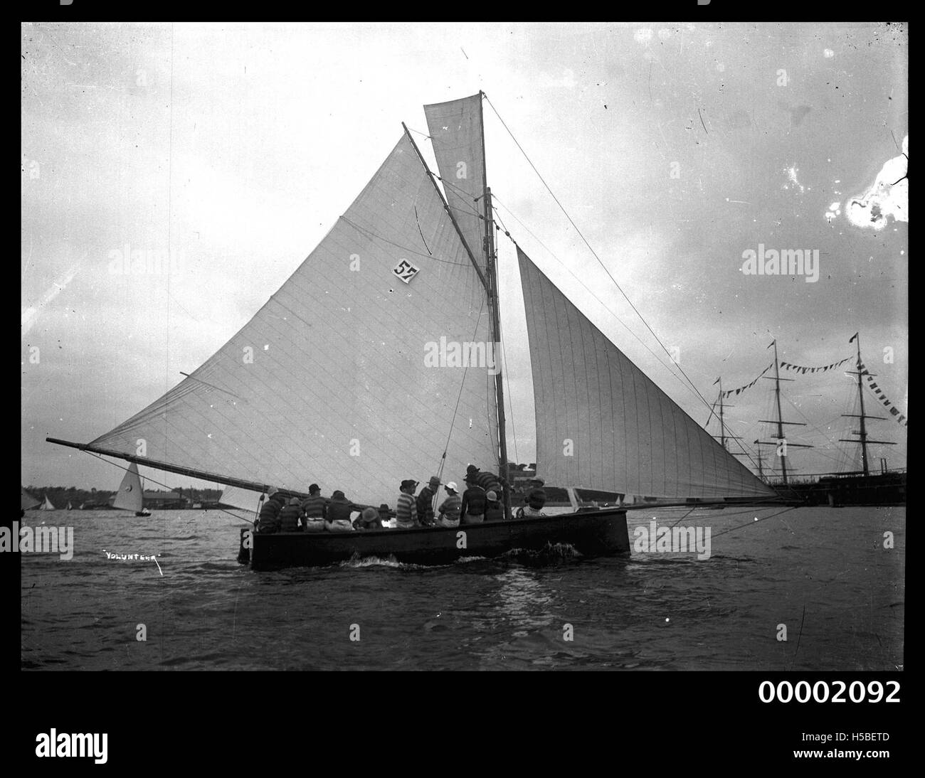 Il VOLONTARIO DI 24 piedi è raffigurato navigare nel porto di Sydney. Questo yacht da corsa, noto per le sue dimensioni compatte e l'agilità, fa parte della vibrante cultura velica di Sydney. La scena mette in evidenza la bellezza del porto e la comunità di barche attive che prospera in questa iconica città australiana. Foto Stock