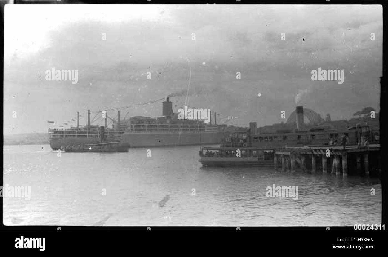 La SS Orsova è visibile nel porto di Sydney, con il Sydney Harbour Bridge visibile sullo sfondo. Questa immagine probabilmente raffigura una scena marittima storica del XX secolo, che mostra l'iconica nave e punto di riferimento. Foto Stock