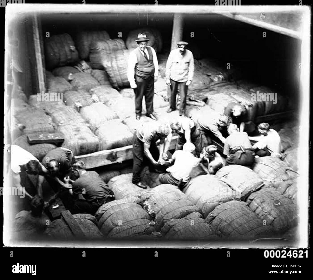 Una fotografia che cattura gli uomini che mettono in sicurezza balle di lana nella stiva della nave MAGDELENE VINNEN nel marzo 1933, che riflette il commercio di lana e il trasporto marittimo dei primi anni del XX secolo. Foto Stock