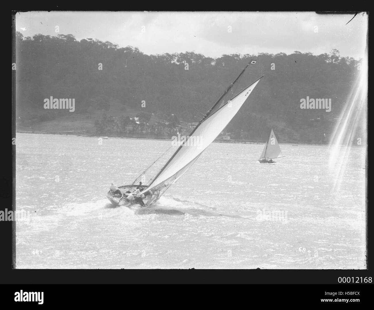 Lo yacht RAWHITI gareggia nella Pittwater Regatta del 1921, mostrando la sua esperienza nel corso di uno dei prestigiosi eventi velici australiani. Questa fotografia cattura l'eleganza e la tradizione della navigazione competitiva sulle acque di Pittwater. Foto Stock