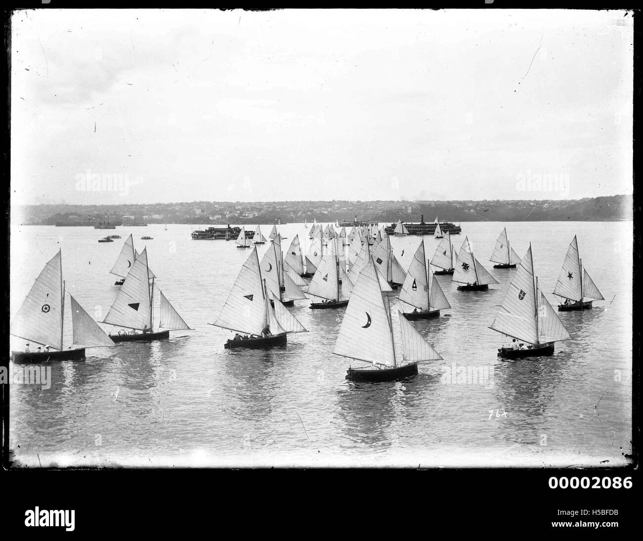 Questo titolo si riferisce probabilmente a un tipo di barca conosciuta come un 18 piedi, utilizzata per competizioni di vela o attività ricreative nel porto di Sydney. Queste barche sono note per la loro velocità e agilità, che le rendono una scelta popolare per le corse nel porto. Foto Stock