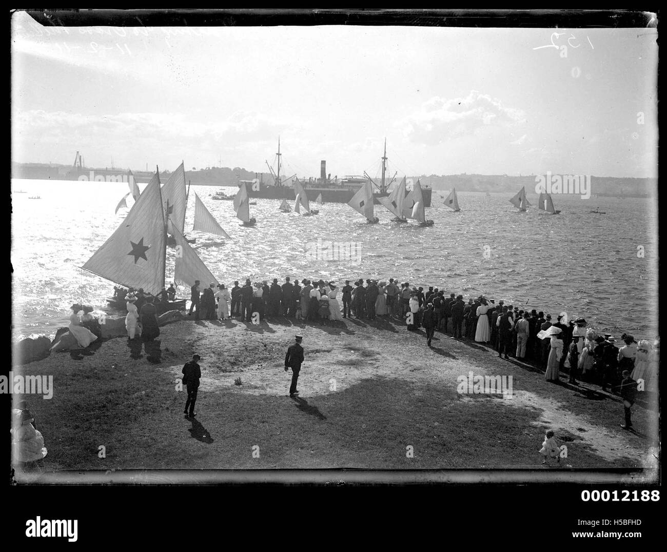 Gli spettatori si riuniscono a Clark Island per assistere all'inizio di una gara di 18 metri, un tipo di evento velico competitivo. Questa foto probabilmente cattura l'emozione e la tradizione delle competizioni veliche nella regione. Foto Stock