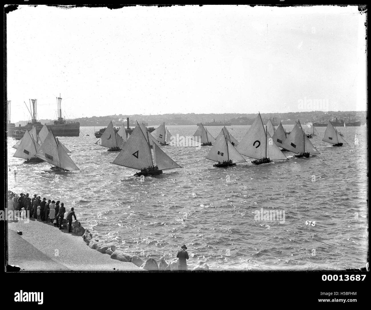 Una fotografia che cattura l'inizio di una gara di 18 metri sul porto di Sydney. L'immagine mette in evidenza l'emozione e lo spirito competitivo di questa gara di vela, che è un evento significativo nella cultura marittima di Sydney. Foto Stock