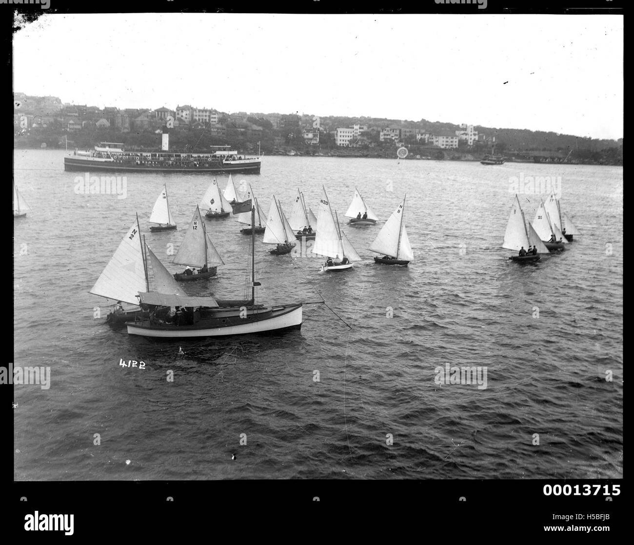 Le gare di sci si fermano davanti a una barca a vela nel porto di Sydney, catturando un momento di attività di vela competitiva in uno dei porti più famosi al mondo. La scena mette in risalto la dinamica cultura marittima di Sydney. Foto Stock